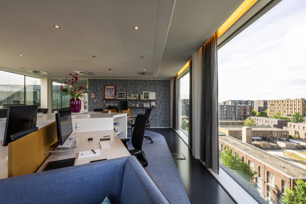 Modern office space on Krijn Taconiskade with large windows overlooking a residential area.